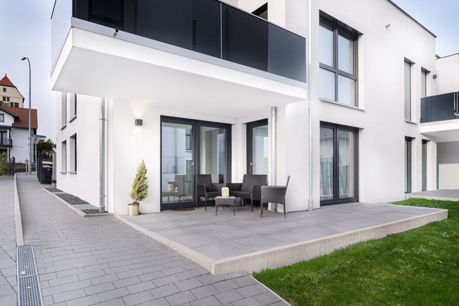 Terrasse mit Rasen vor einem Neubau